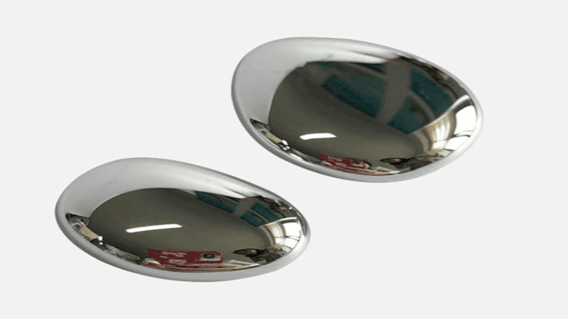 Two polished, silver-colored oval metal pebble objects on a plain white background