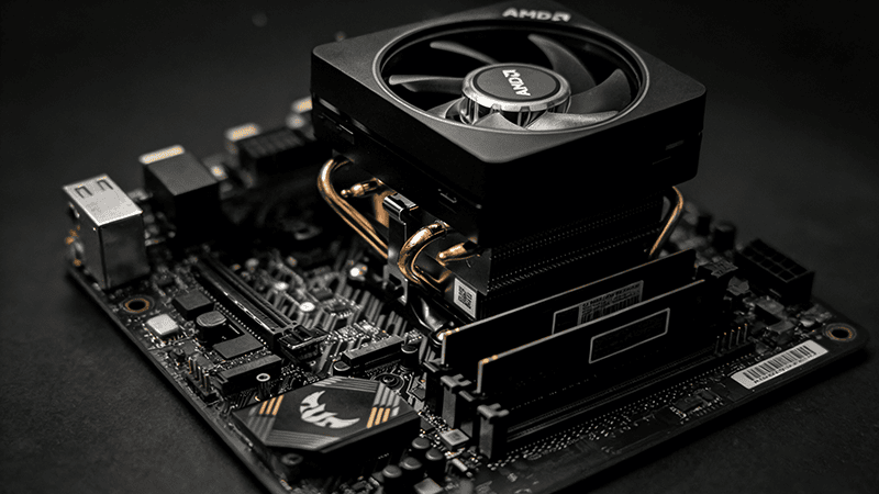 AMD CPU cooler (with copper heat pipes) mounted on a black motherboard, highlighting the CPU and nearby circuit components