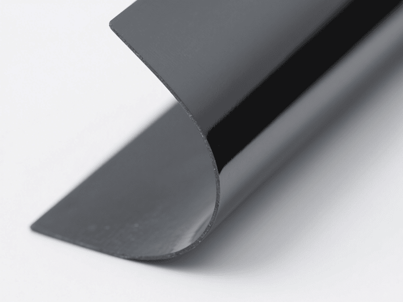 Primer plano de una lámina de material de interfaz térmica (TIM) Jiuju de color gris oscuro y altamente flexible.