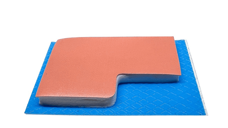 Almohadilla térmica naranja sobre un reverso adhesivo azul, con un diseño recortado